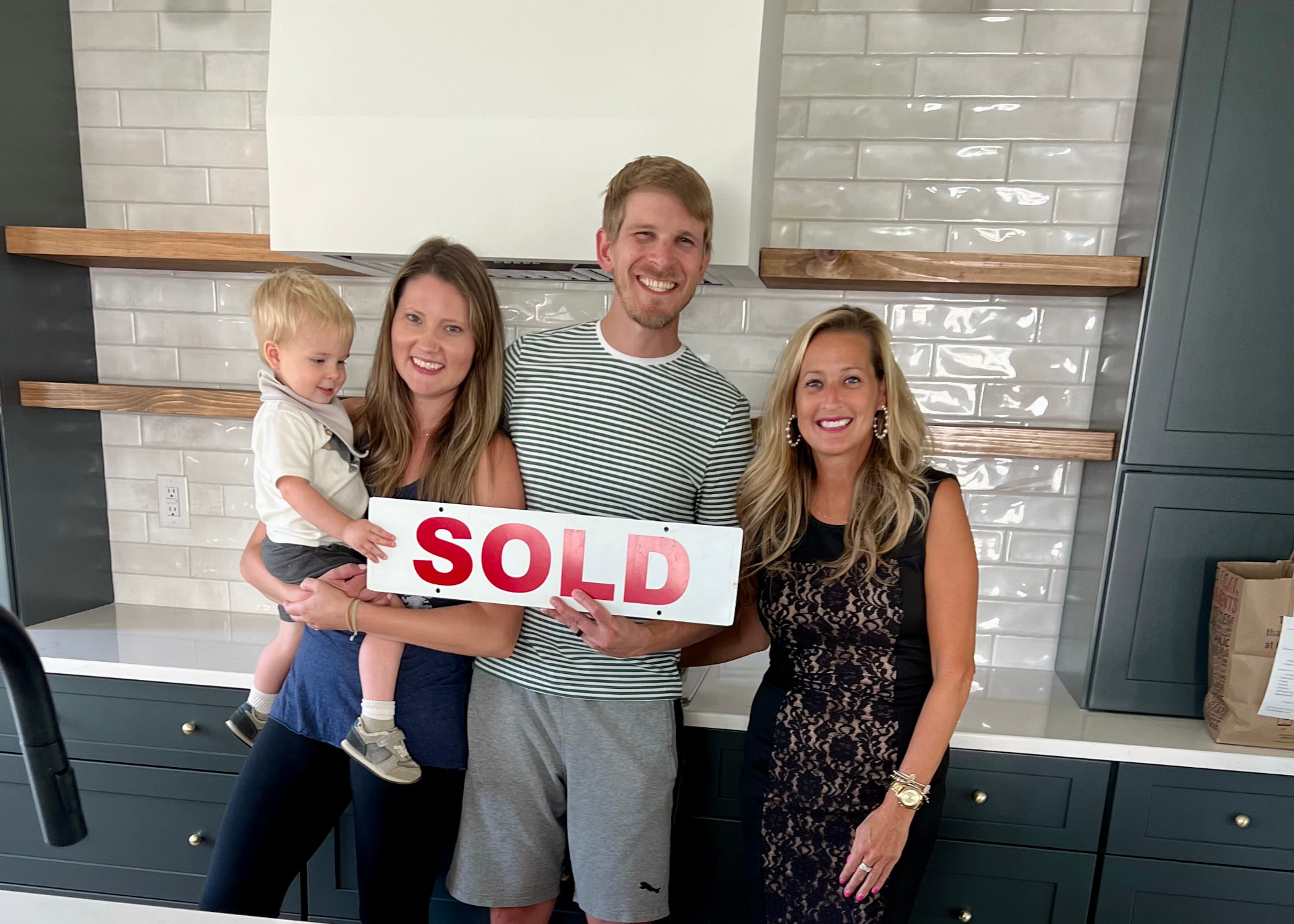 Abby Knarr with a happy Lancaster County family holding a SOLD sign in their new kitchen